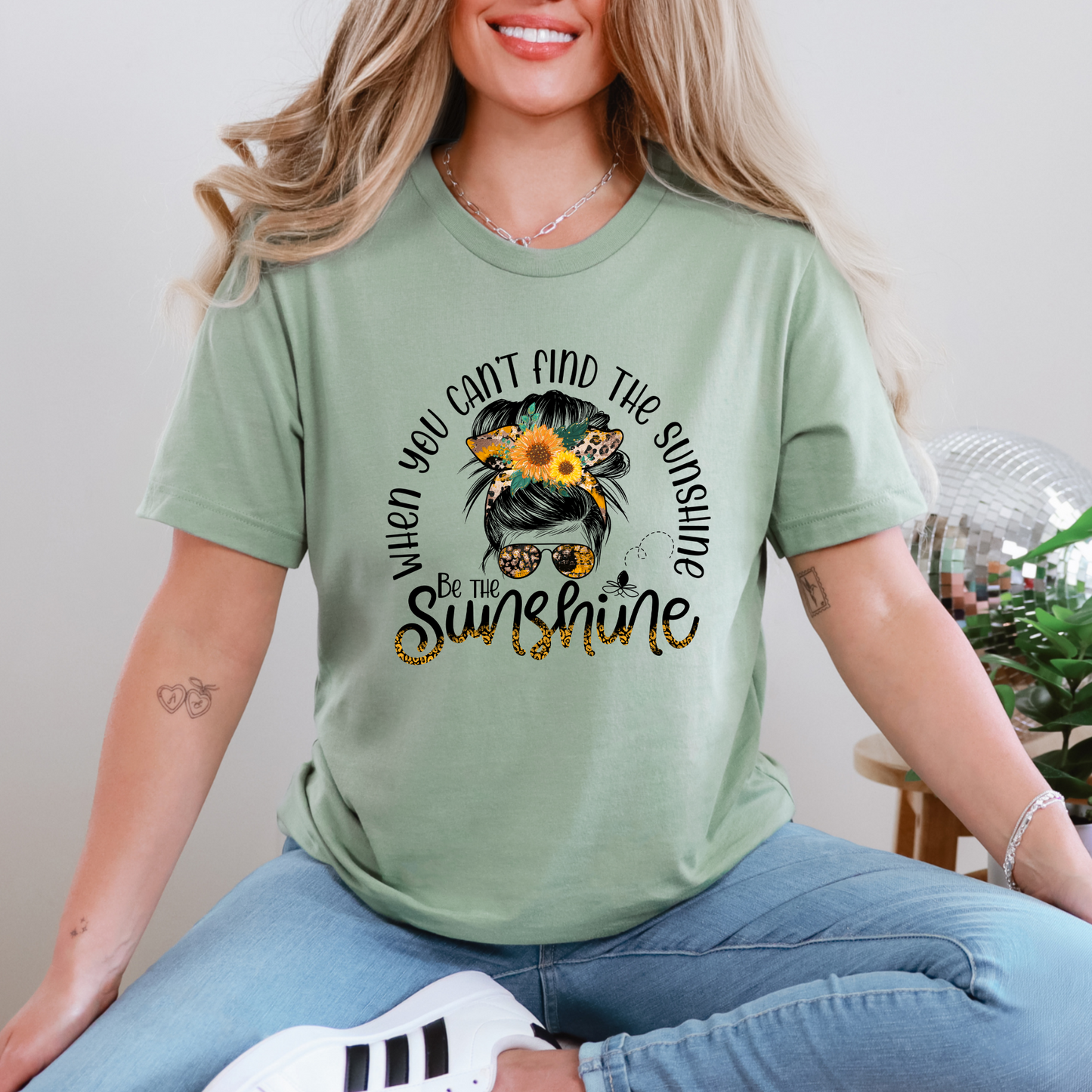 Person wearing a green t-shirt with a sunflower design and text.