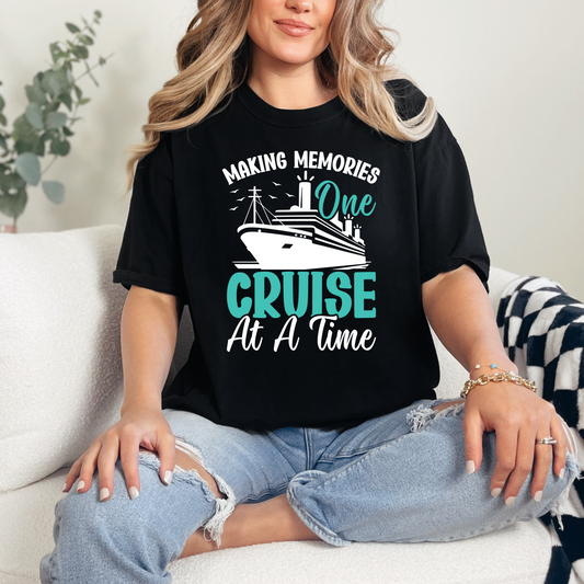Person wearing a black graphic t-shirt with a cruise-themed design, sitting on a couch.