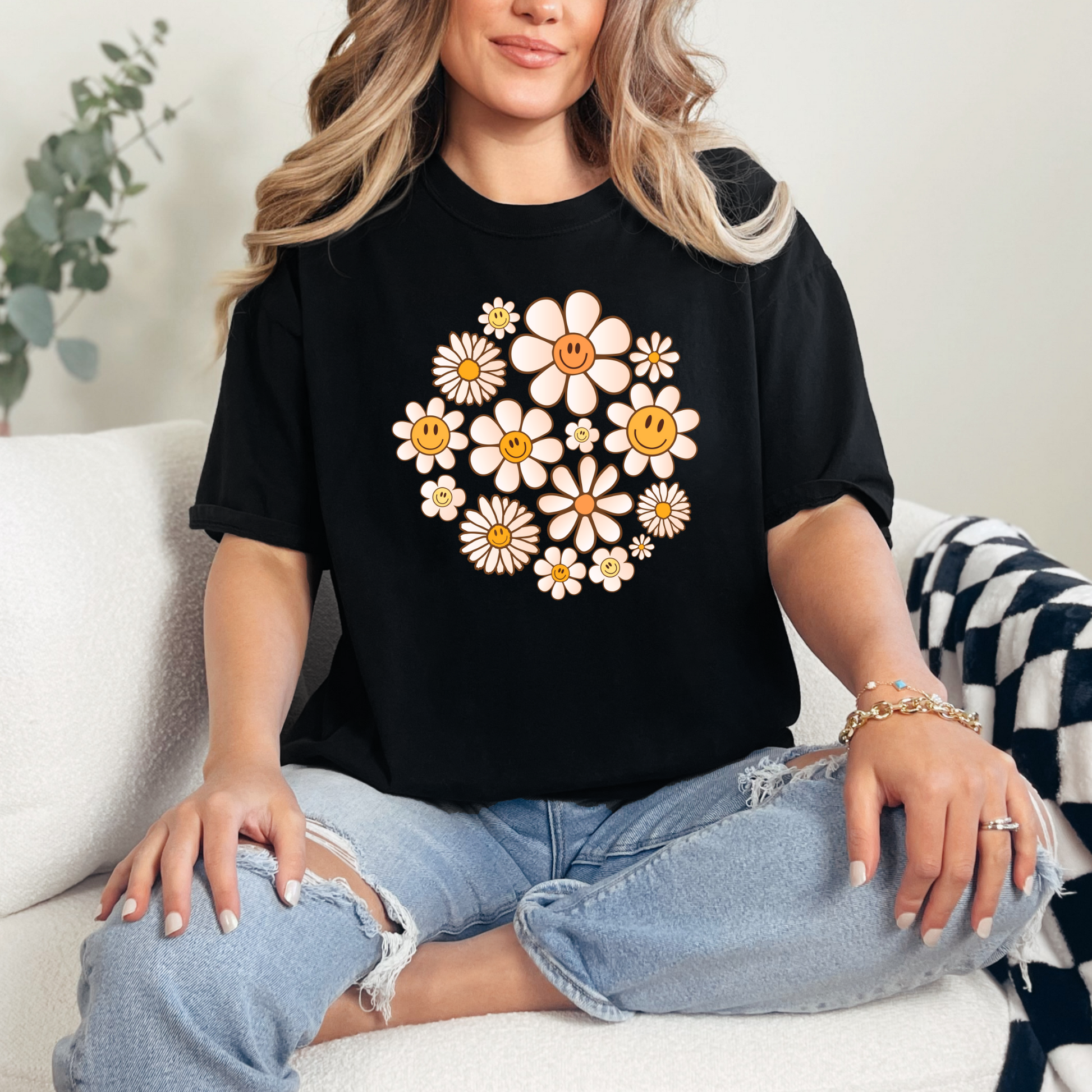 A person wearing a black graphic t-shirt with a design of daisies in a circular pattern.